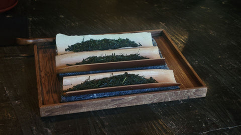 Overhead view of a weathered wooden tea tray holding dark-green powdered tea.