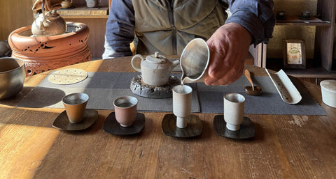 A person preparing tea at a low wooden table