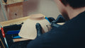 Gloved hands turning a bisque bowl upside down to trim its foot ring at the bench