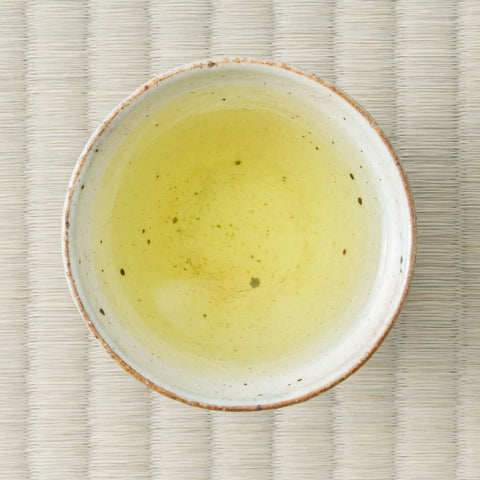 Fujimien sencha brewed to a soft golden-green liquor in a speckled white cup, photographed from above