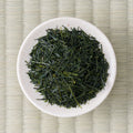 Dry deep-green handpicked Honyama Yabukita sencha leaves in a cream dish, viewed from above.