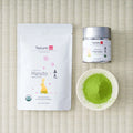 Tezumi Classics Organic Haruto matcha pouch with a rabbit and cherry-blossom design beside a silver tin and a dish of matcha powder.