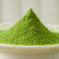 Vivid green Haruto matcha powder heaped in a tall cone in a cream bowl, side view.