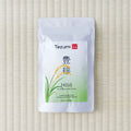 White Tezumi pouch printed 豊穣 / Hōjō Genmaimatcha with a golden rice-ear illustration, flat on a tatami mat