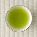 Hōjō Genmaimatcha brewed to a vivid yellow-green in a speckled white cup, photographed from above