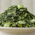 Close-up of Hōjō Genmaimatcha, matcha-dusted green leaf and popped rice heaped in a pale ceramic bowl