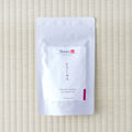 White Tezumi Specialty pouch labelled こうしゅん / Honyama Koushun Bihakkocha with a magenta side tab, flat on tatami