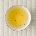 Honyama Koushun bihakkocha brewed pale golden in a speckled white cup, photographed from overhead