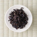 Dark twisted leaves of Honyama Yabukita wakoucha arranged on a small white dish, viewed from directly above
