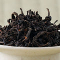 Macro shot of dry Honyama Yabukita wakoucha leaf, long and wiry with reddish stems, mounded in a pale bowl