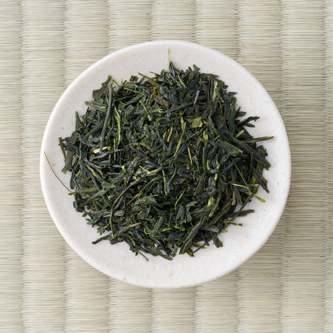 Koshi-no-Sato sencha leaf arranged on a small white dish, slender dark green needles viewed from above