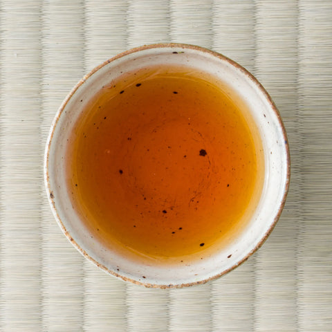 Reddish-amber Kumamoto Koushun wakoucha (Japanese black tea) brewed in a ceramic cup, viewed from above on tatami.