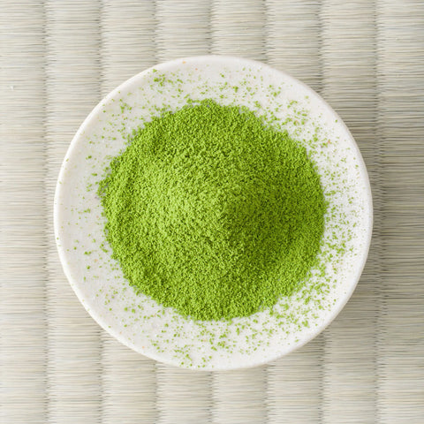 Vivid green Rikyu matcha powder in a small cream dish, viewed from above.