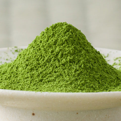 Vivid green Rikyu matcha powder mounded in a ceramic bowl, side view.