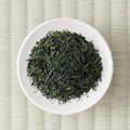 Dry deep-green Ryokuin sencha leaves in a cream dish, viewed from above.