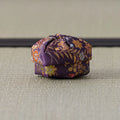 Deep purple silk kogo patterned with gold and orange foliage, shown from the side on tatami
