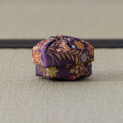 Deep purple silk kogo patterned with gold and orange foliage, shown from the side on tatami