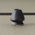 Three-quarter view of the bronze-glazed kusenaoshi showing its ribbed, tapering form