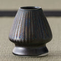 Side view of the dark fluted kusenaoshi whisk stand on tatami