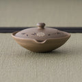 Pale beige unglazed shiboridashi handleless teapot with a domed lid, front view on tatami