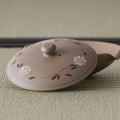 Three-quarter view of the shiboridashi showing the carved floral decoration on the lid