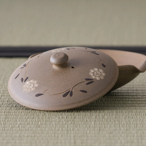 Three-quarter view of the shiboridashi showing the carved floral decoration on the lid
