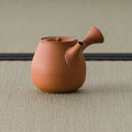Orange-red kyusu with the side handle angled toward the viewer