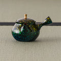 Front view of the green-gold kyusu showing the lid and gold knob