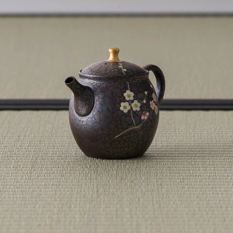 Rear three-quarter view of the bronze teapot showing the upright loop handle