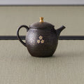 Side view of the dark teapot showing the spout, handle and rounded body