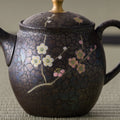 Close-up of the teapot body showing the painted cherry-blossom decoration near the base