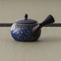 Side view of the dark floral kyusu with the side handle angled toward the viewer