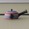 Pink-and-blue patterned kyusu teapot, three-quarter view with the spout to the right
