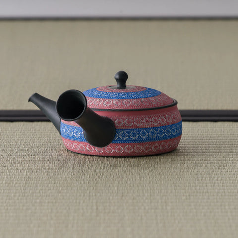 Side view of the reddish-pink kyusu with the spout to the right