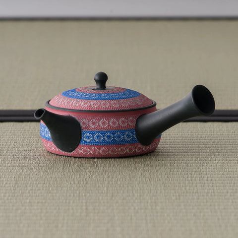 Reddish-pink shudei side-handle kyusu with blue inlaid ring-pattern bands, spout to the left on tatami