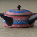 Overhead three-quarter view of the pink kyusu showing the side handle and blue bands