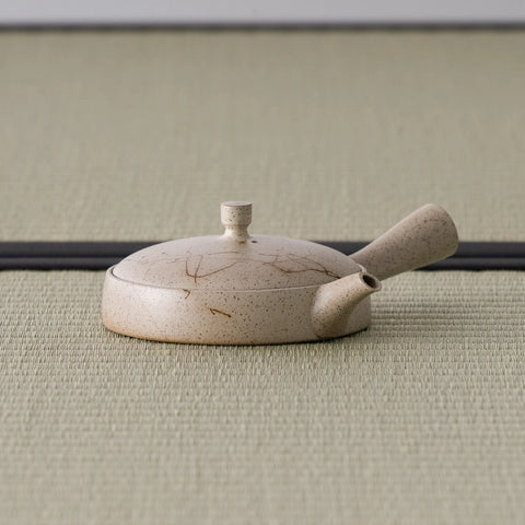 Side view of the low beige kyusu showing its broad flat body and side handle