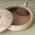 Close-up of the flat kyusu with the lid set ajar, showing the interior