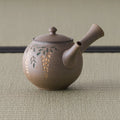 Side view of the kyusu showing the hollow side handle and engraved floral motif