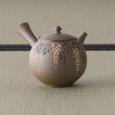 Grey-brown tokoname side-handle kyusu with carved floral decoration, spout to the right on tatami