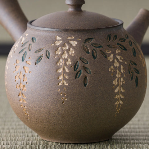 Close-up of the kyusu body showing the carved gold-tan bush-clover floral design