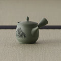 Sage-green celadon side-handle kyusu with carved decoration, spout to the left on tatami
