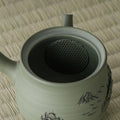 Close-up into the green kyusu interior showing the built-in mesh strainer