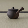 Side view of the reddish-brown kyusu showing the chattered surface and side handle