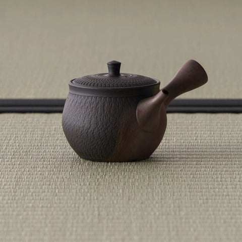 Side view of the reddish-brown kyusu showing the chattered surface and side handle