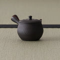Rear three-quarter of the carved kyusu showing the hollow side handle and textured body