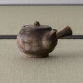 Side view of the earthy brown kyusu showing the side handle and natural ash coloring