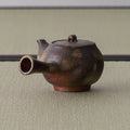 Close view of the kyusu's spout opening and rounded wood-fired body