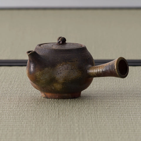 Rear three-quarter of the kyusu showing the hollow side handle and mottled surface