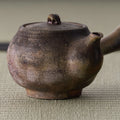 Close-up of the wood-fired kyusu body showing its rough ash-flecked surface